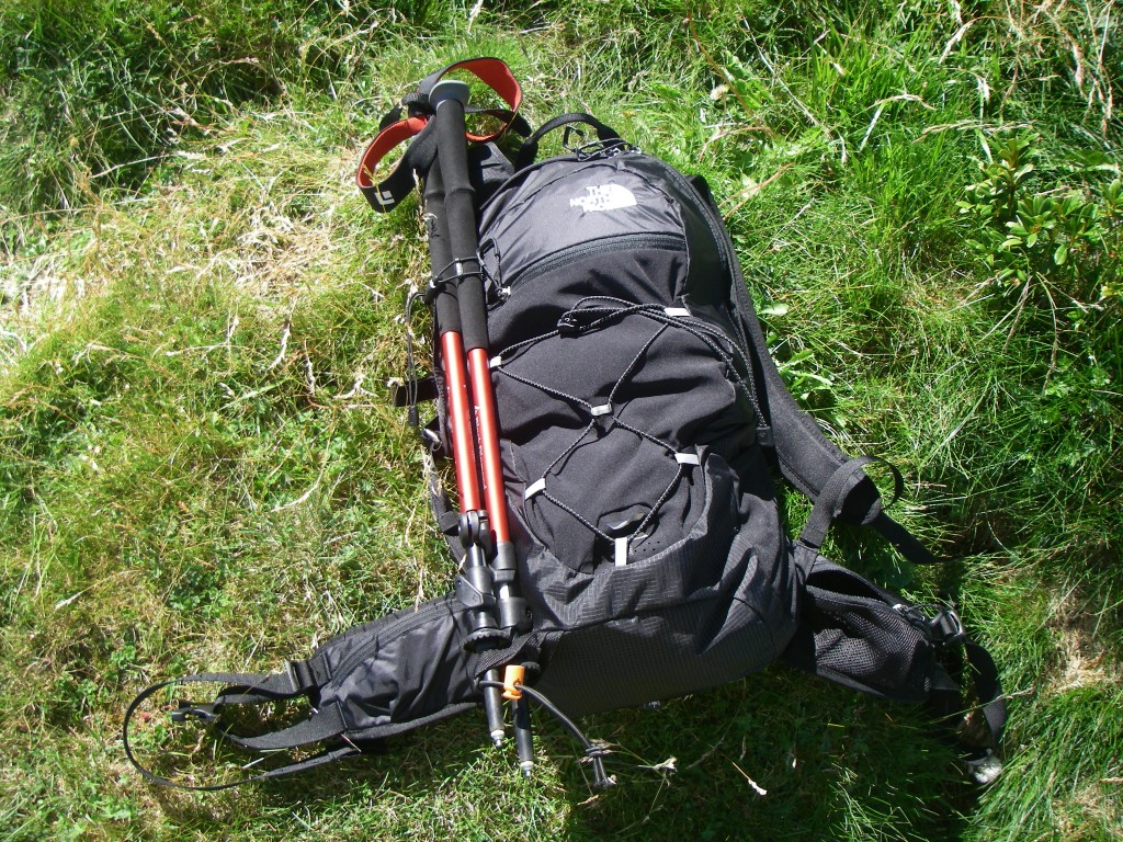 Vue de l'extérieur du sac avec les 2 poches sur la ceinture dont une en mesh, le porte-matériel avec l'élastique et la fixation pour les bâtons. À noter aussi la poche extérieure en tissu stretch